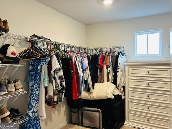 a view of walk in closet with clothes and shoes