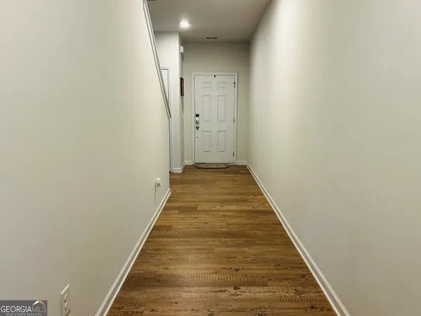 a view of a hallway with wooden floor and staircase