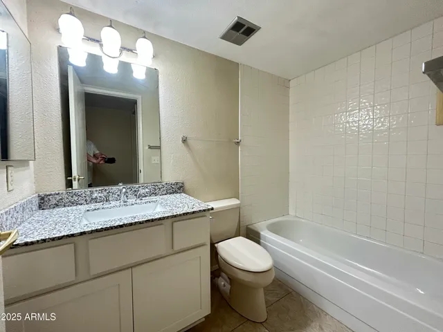 a bathroom with a granite countertop sink a toilet and bathtub