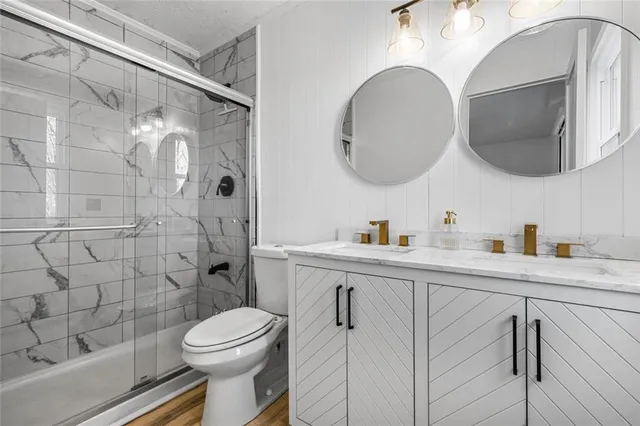 a bathroom with a toilet a sink a mirror a vanity and shower