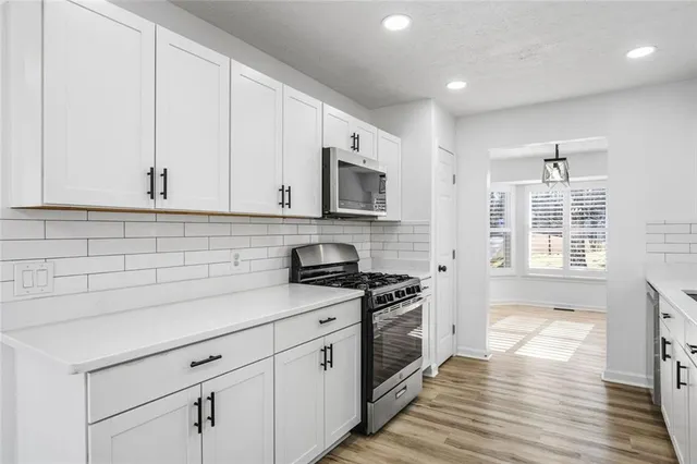a kitchen with granite countertop white cabinets and stainless steel appliances