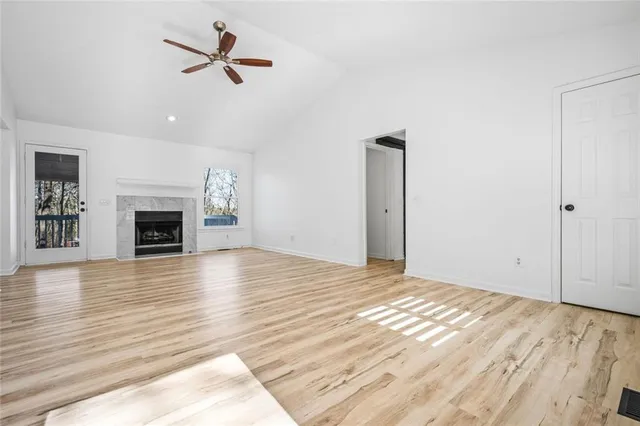 an empty room with wooden floor fireplace and ceiling fan