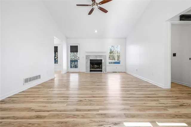 an empty room with wooden floor fireplace and windows