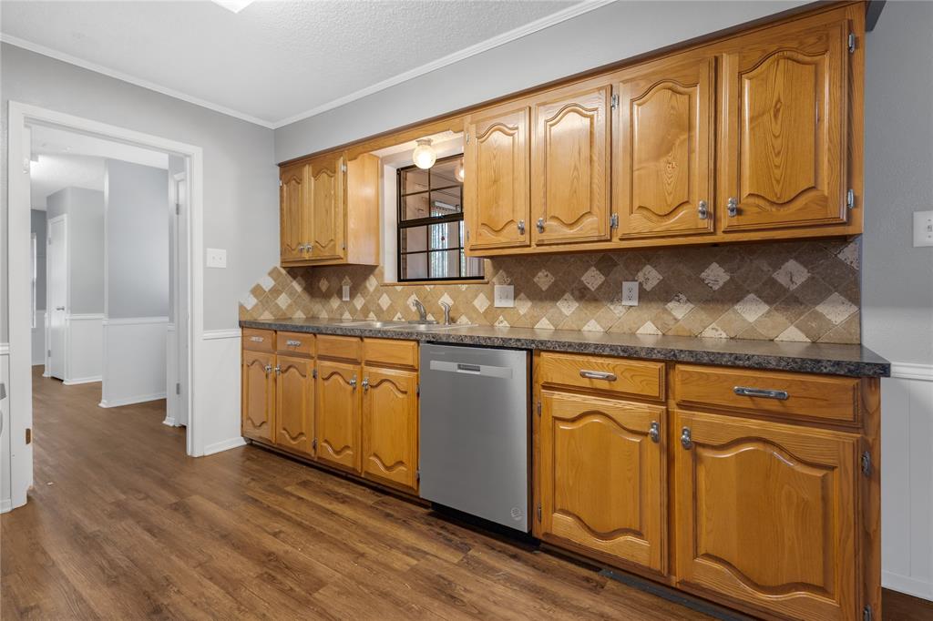 1609 Robin Street Mineola, TX 75773 - Photo 6 of 24 Kitchen featuring wood-finish flooring, light wood cabinetry, a patterned tile backsplash, dark countertops, and a built-in dishwasher