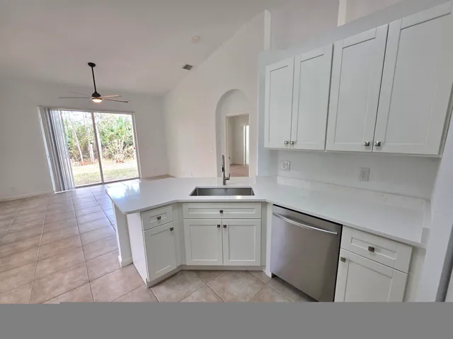 a kitchen with stainless steel appliances a refrigerator a stove a sink dishwasher and white cabinets with wooden floor