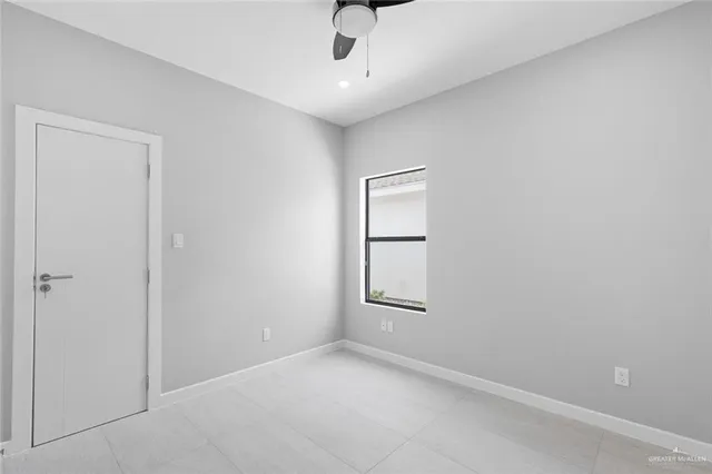 an empty room with windows and ceiling fan