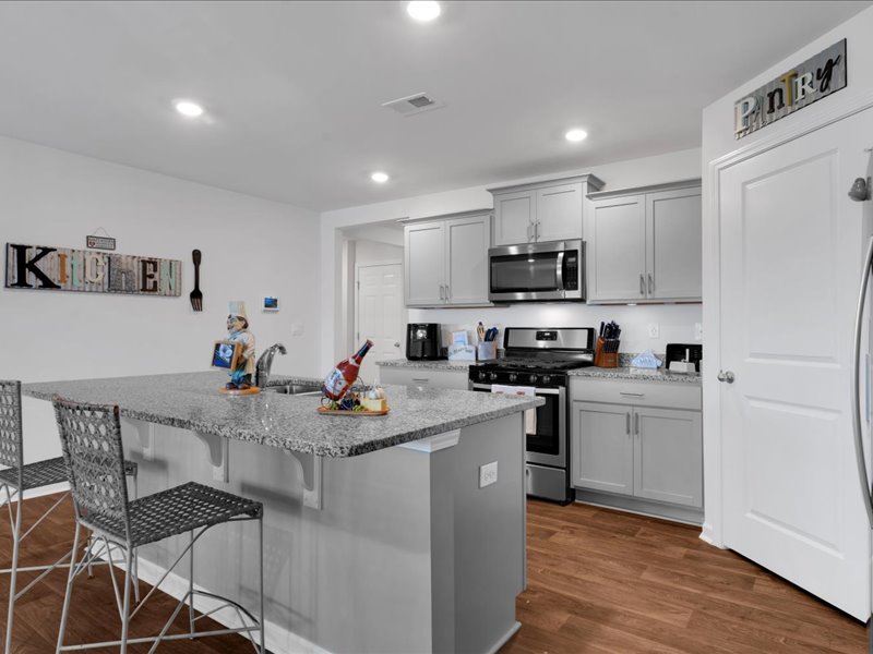 525 Ashwood Way Easley, SC 29640 - Photo 7 of 36 This modern kitchen features a spacious island, sleek appliances, and durable hardwood flooring.