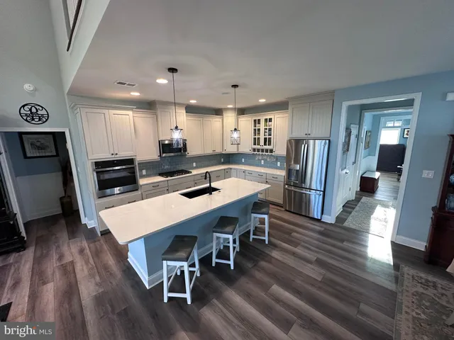 a kitchen with stainless steel appliances granite countertop a stove a refrigerator a dining table and chairs with wooden floor