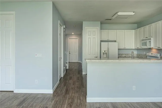 a kitchen with kitchen island granite countertop white cabinets and refrigerator