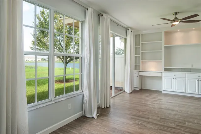 a view of an empty room with a window and wooden floor