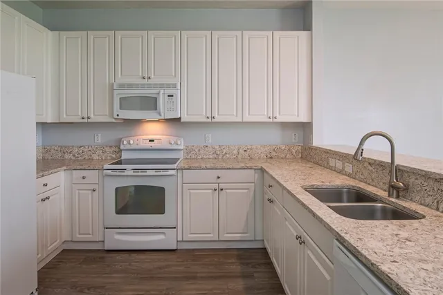a kitchen with granite countertop white cabinets and white appliances