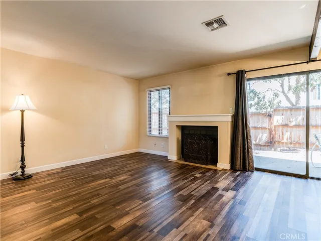 an empty room with wooden floor fireplace and windows