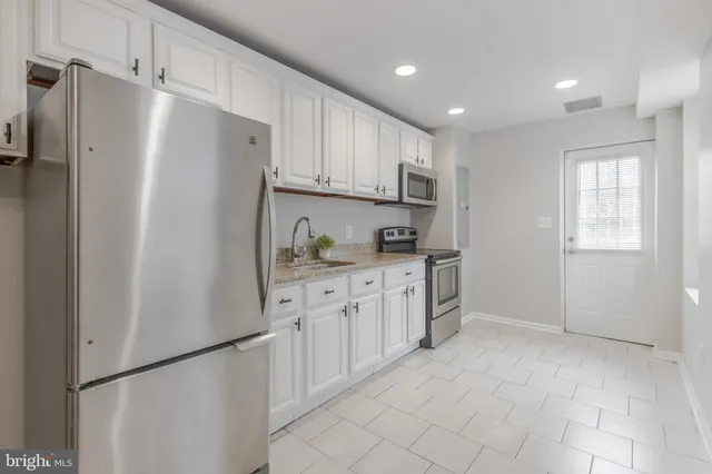 a kitchen with white cabinets and refrigerator