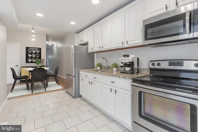 a kitchen with stainless steel appliances granite countertop a stove a sink and a microwave