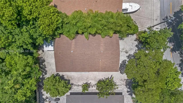 an aerial view of a house with a yard and a forest