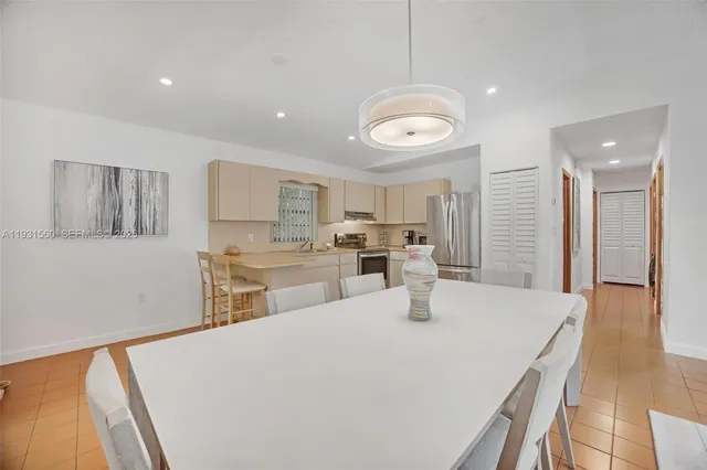 a kitchen with stainless steel appliances kitchen island granite countertop a refrigerator a stove a sink dishwasher and white cabinets with wooden floor