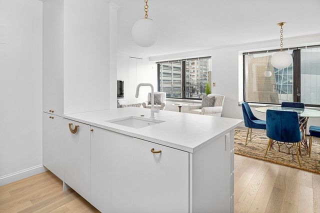a kitchen with a sink a counter top space and living room view