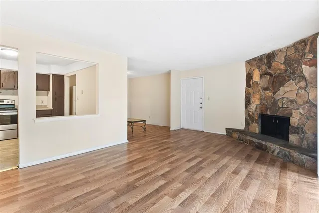 a view of an empty room with wooden floor and a fireplace