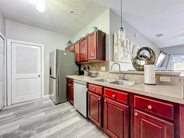 a kitchen with stainless steel appliances granite countertop a sink dishwasher stove and refrigerator with wooden floor