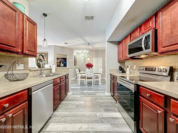 a large kitchen with stainless steel appliances granite countertop a stove top oven a sink dishwasher and cabinets with wooden floor