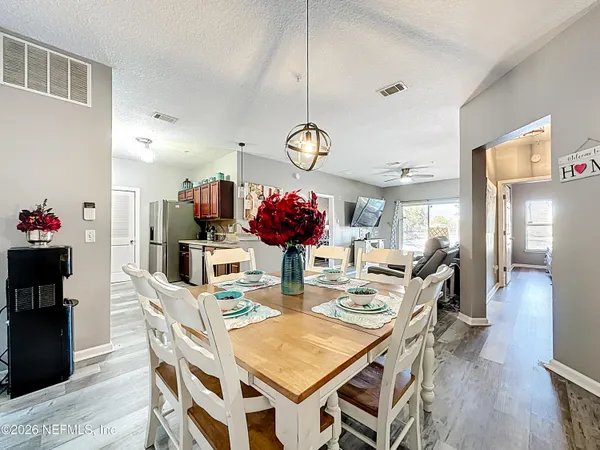 a view of a dining room and livingroom with furniture wooden floor a chandelier
