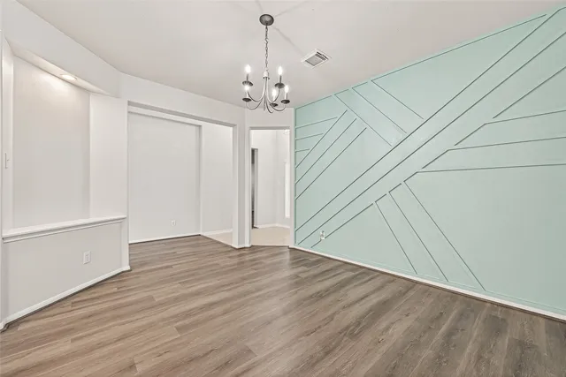 an empty room with wooden floor fireplace and windows