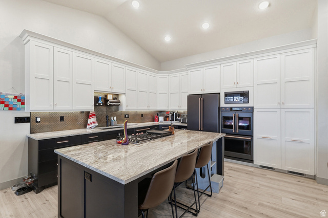 175 North 100 West Providence, UT 84332 - Photo 7 of 45 Kitchen featuring vaulted ceiling, double wall oven, light stone counters, a center island, and a breakfast bar