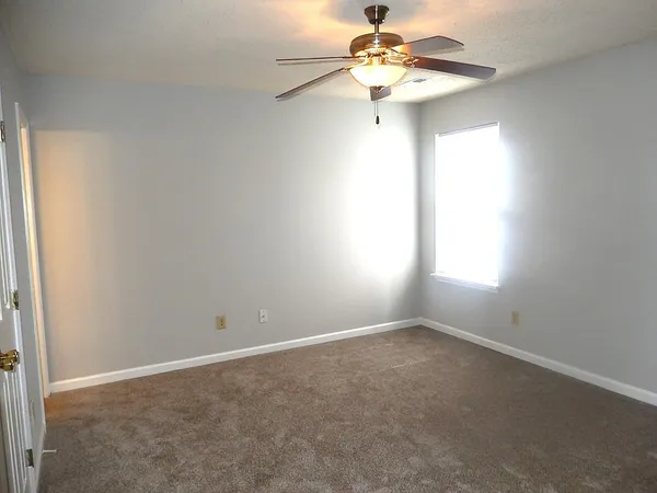 an empty room with a window and a fan