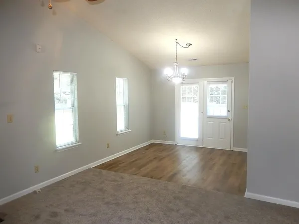 an empty room with windows and chandelier fan