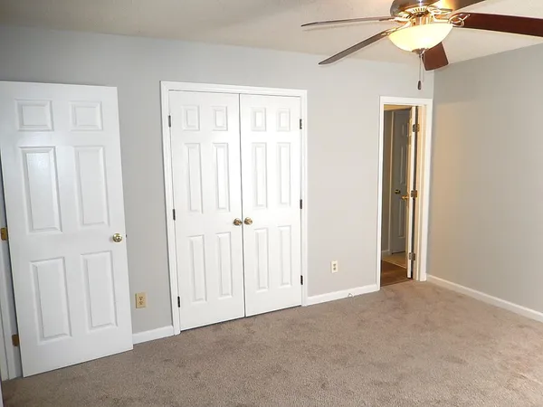 an empty room with windows and fan