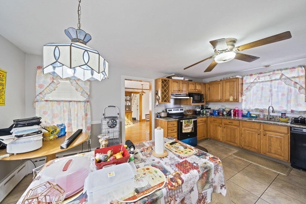 14 Foster Street Avon, MA 02322 - Photo 15 of 33 a kitchen with stainless steel appliances granite countertop a sink a stove top oven a chimney and a dining table