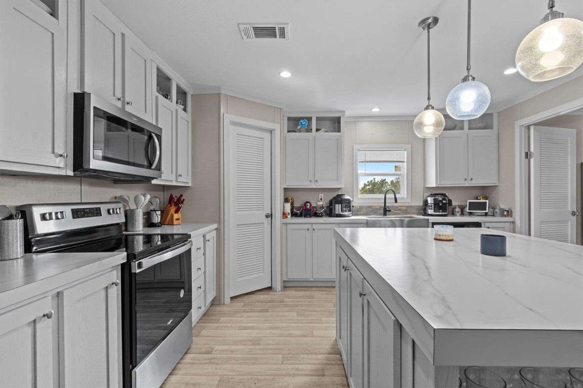 480 Grandpa Road Lockhart, TX 78644 - Photo 8 of 32 a kitchen with stainless steel appliances granite countertop a stove top oven a refrigerator a sink and dishwasher with white cabinets
