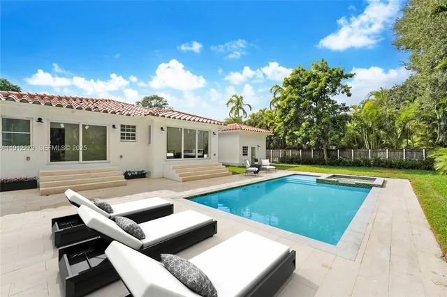 a view of pool with lawn chairs and large trees