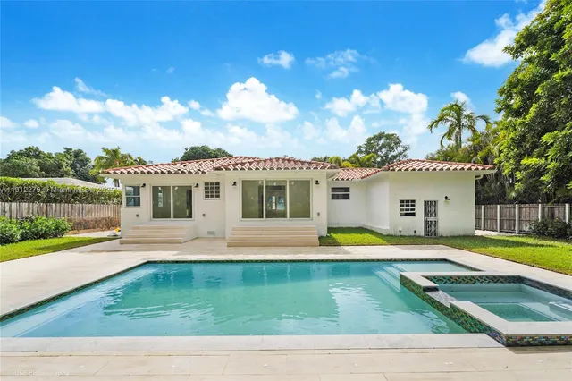 a view of pool with lawn chairs and large trees