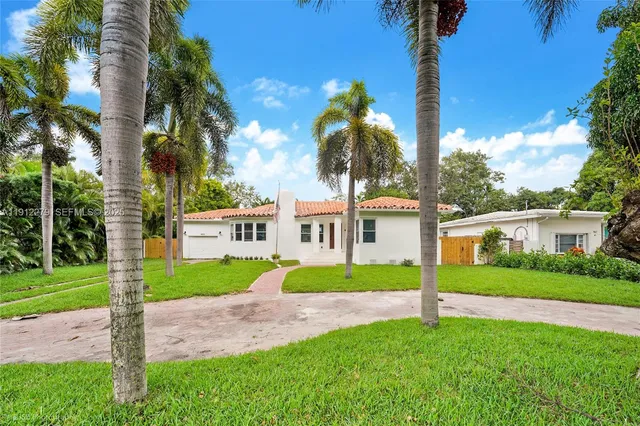 a view of a house with a yard and palm trees