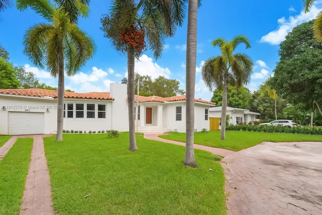 a view of a house with a yard and palm trees