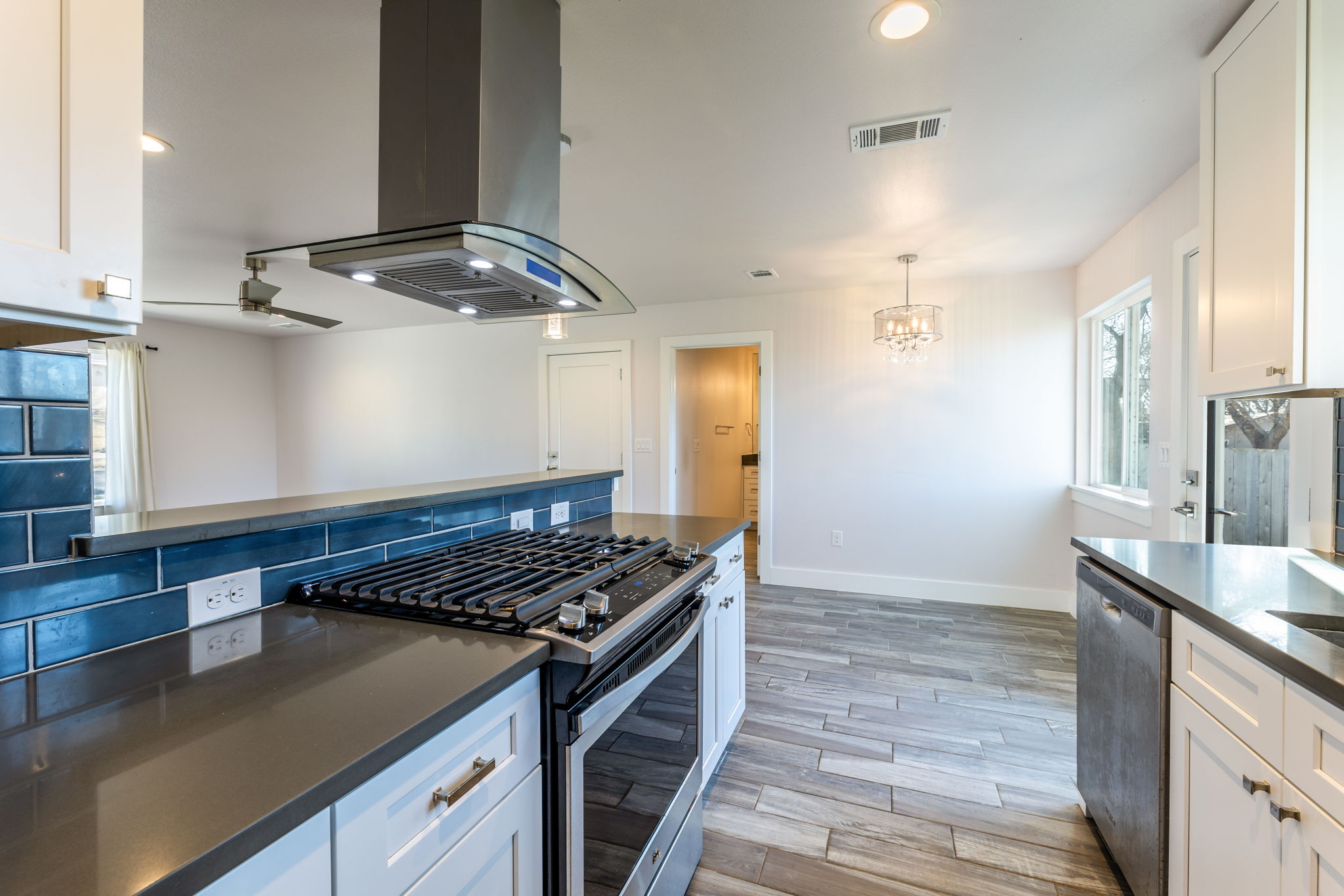 8410 Romney Road Austin, TX 78748 - Photo 11 of 35 Kitchen featuring white cabinetry, stainless steel appliances, island range hood, wood finish floors, and a ceiling fan