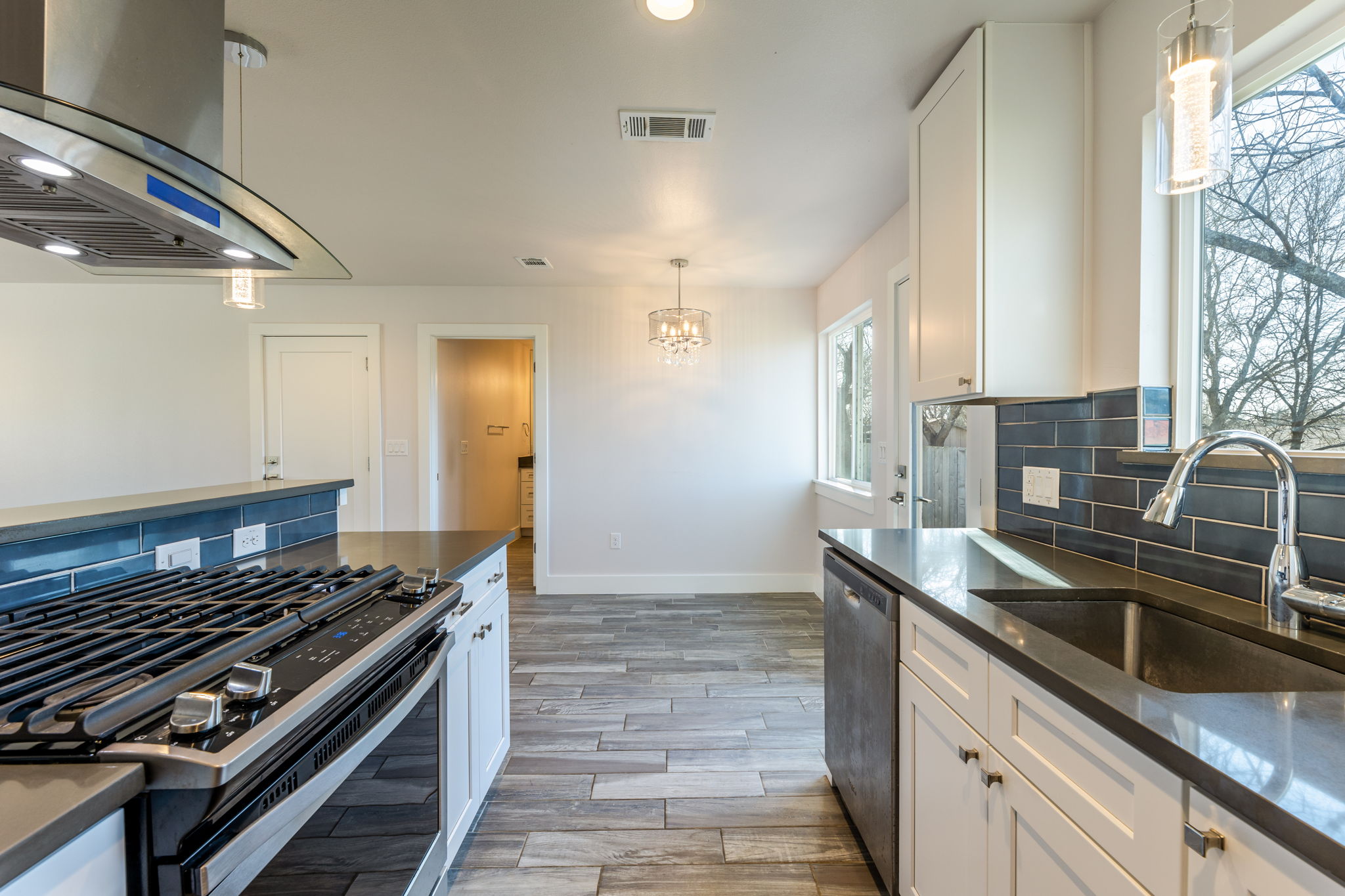 8410 Romney Road Austin, TX 78748 - Photo 12 of 35 Kitchen with stainless steel appliances, white cabinets, ventilation hood, and tasteful backsplash