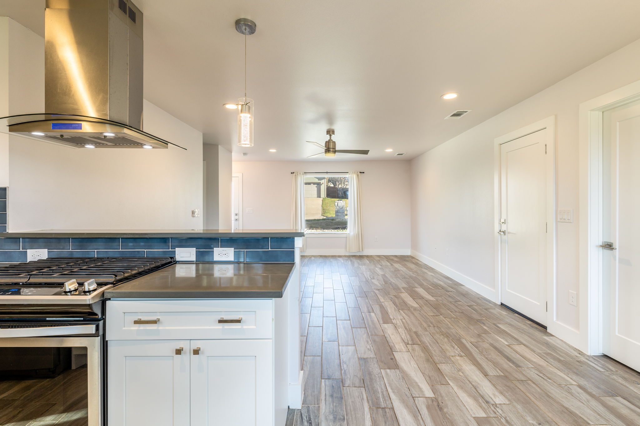 8410 Romney Road Austin, TX 78748 - Photo 14 of 35 Kitchen featuring stainless steel gas range, island range hood, white cabinets, wood tiled floors, and pendant lighting