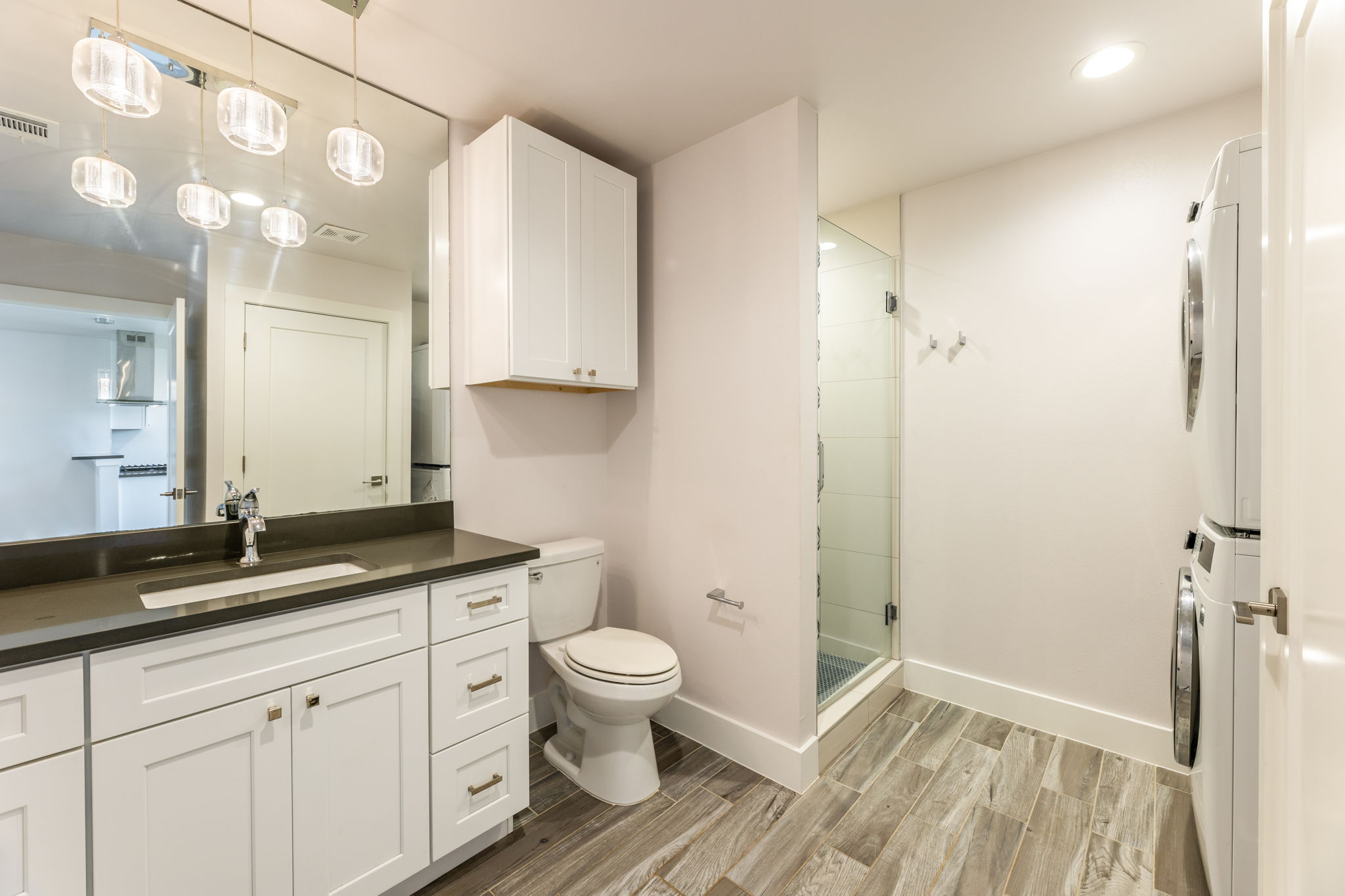 8410 Romney Road Austin, TX 78748 - Photo 19 of 35 Bathroom featuring wood tiled floors, vanity, a shower stall, stacked washer / drying machine, and recessed lighting