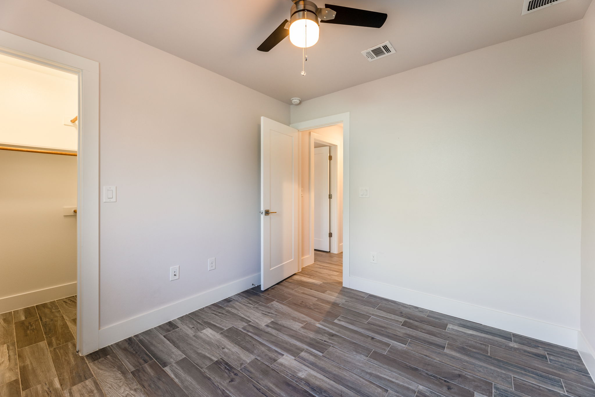 8410 Romney Road Austin, TX 78748 - Photo 24 of 35 Unfurnished bedroom featuring wood tiled floors, ceiling fan, and a walk in closet