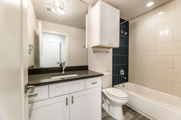 a bathroom with a granite countertop sink toilet mirror and bathtub