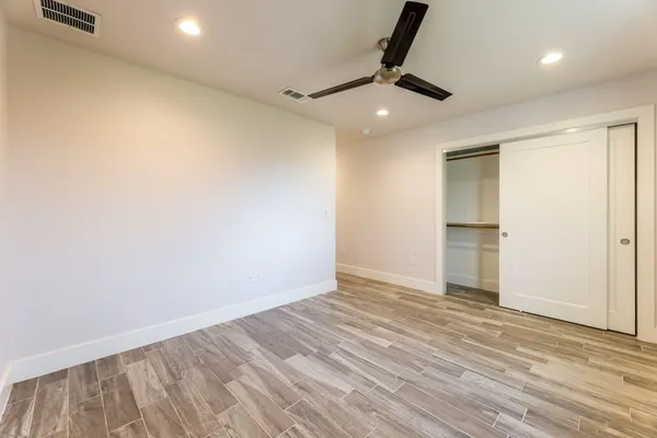 an empty room with wooden floor cabinet and a ceiling fan
