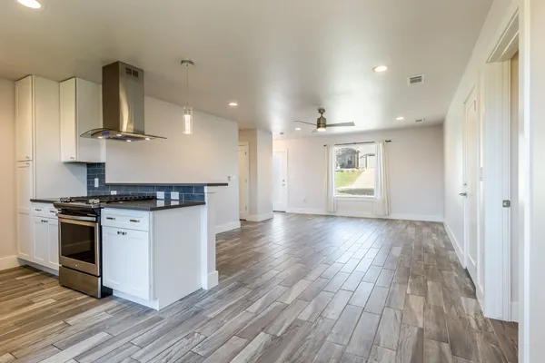 a kitchen with stainless steel appliances granite countertop a stove and a wooden floors