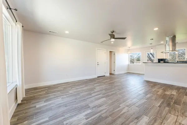 an empty room with wooden floor and windows