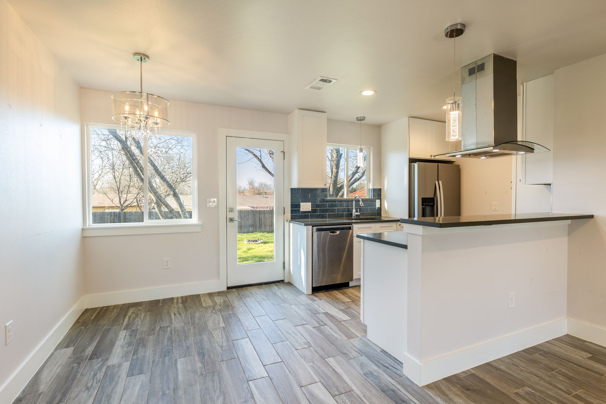 8410 Romney Road Austin, TX 78748 - Photo 8 of 35 Kitchen featuring ventilation hood, light wood-type flooring, white cabinets, stainless steel appliances, and a peninsula