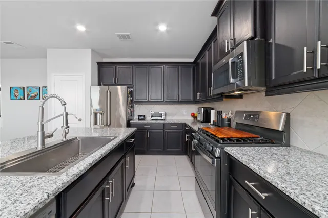 a kitchen with granite countertop a sink stove and refrigerator