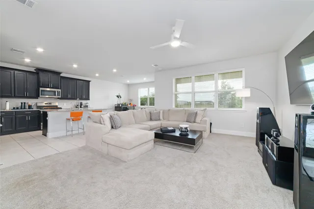 a living room with furniture and a flat screen tv with kitchen view