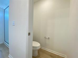 213 Saide Street Georgetown, TX 78626 - Photo 23 of 32 Water closet with a white toilet, chrome toilet paper holder, wood-finish flooring, and white baseboards