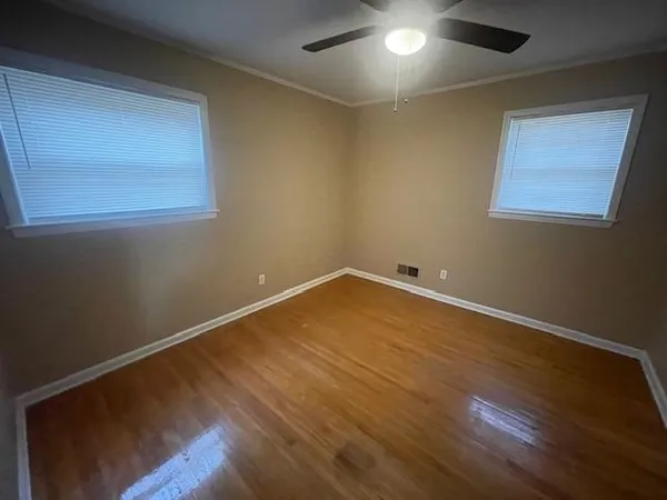 an empty room with wooden floor and windows